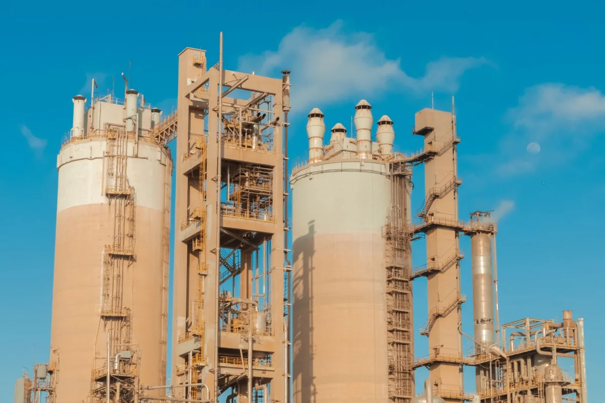 Torres de perolação de ureia e estruturas metálicas com escadas e tubulações de uma planta de fertilizantes nitrogenados sob céu azul
