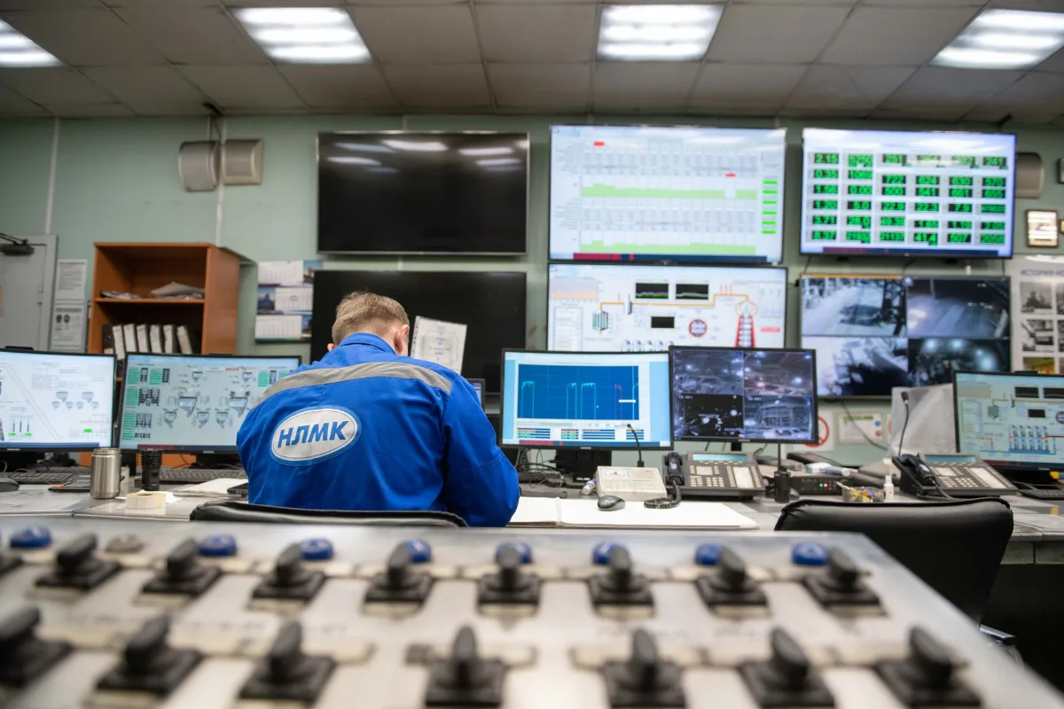 Engenheiro acompanhando vários monitores numa sala de controle industrial